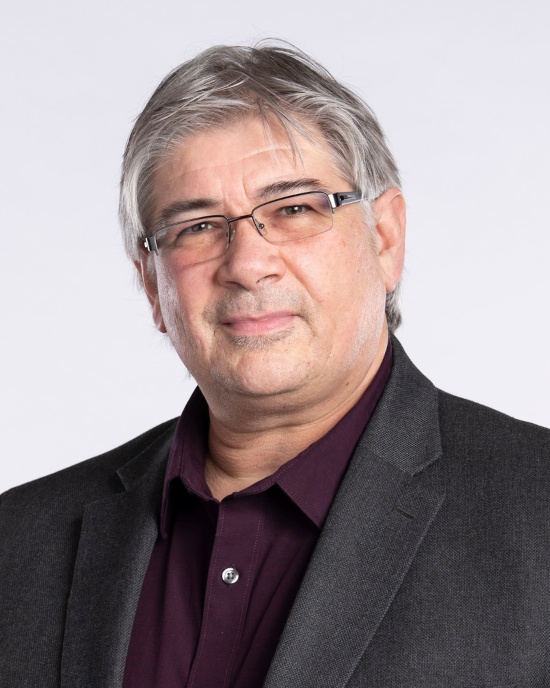 Jeff Cleland with gray hair and glasses, wearing a dark blazer and maroon shirt