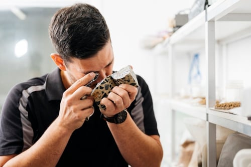 Kiwa KOAC laborary employee inspecting asphalt with a magnifying glass in a laboratory setting