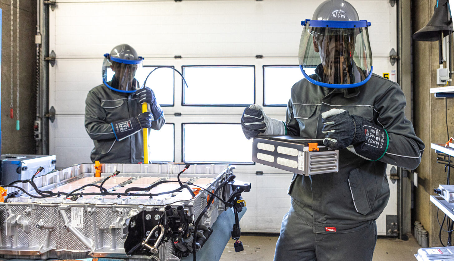 Vinçotte Technicians in protective gear working on electric vehicle battery testing in a testenvironment