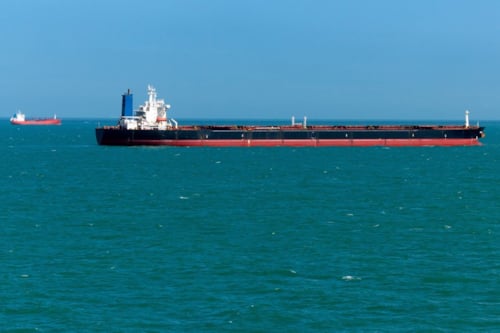 Cargo ship sailing in calm blue ocean under clear sky