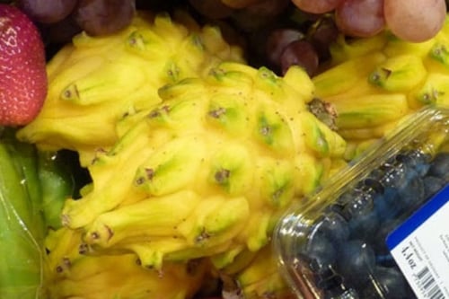 Variedad de frutas como uvas, fresas, pitayas amarillas, guanábanas, mangos, granadas, bananos y arándanos en un arreglo colorido.