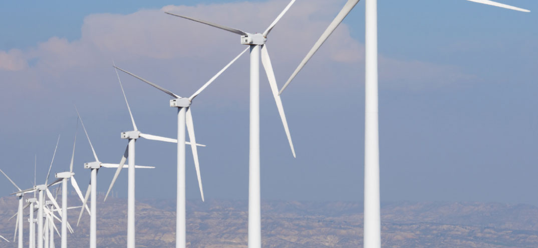 Parque eólico con aerogeneradores blancos alineados bajo un cielo despejado.