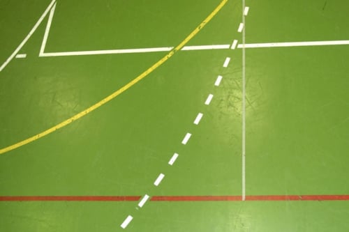 Groene sportvloer met witte, gele en rode lijnen voor speelvelden.