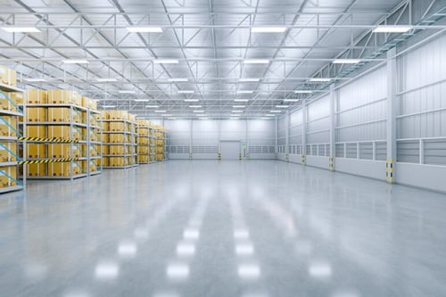 Een grote, moderne magazijnruimte met rekken gevuld met gele dozen en een glanzende betonnen vloer.