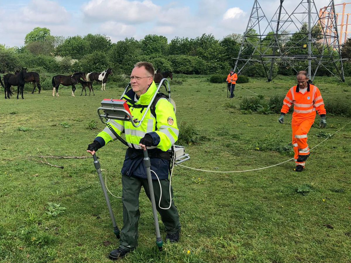 Twee medewerkers in opvallende veiligheidskleding meten met apparatuur