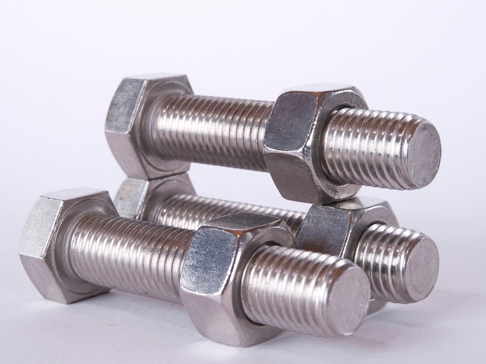 Set van drie metalen bouten en moeren op een witte achtergrond.