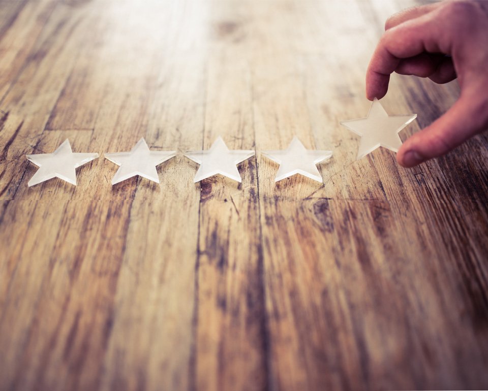 En gengrebild som visar en hand som placerar en stjärna bland fyra andra stjärnor på ett träbord som exemplifierar metodisk process för att nå framgång. 