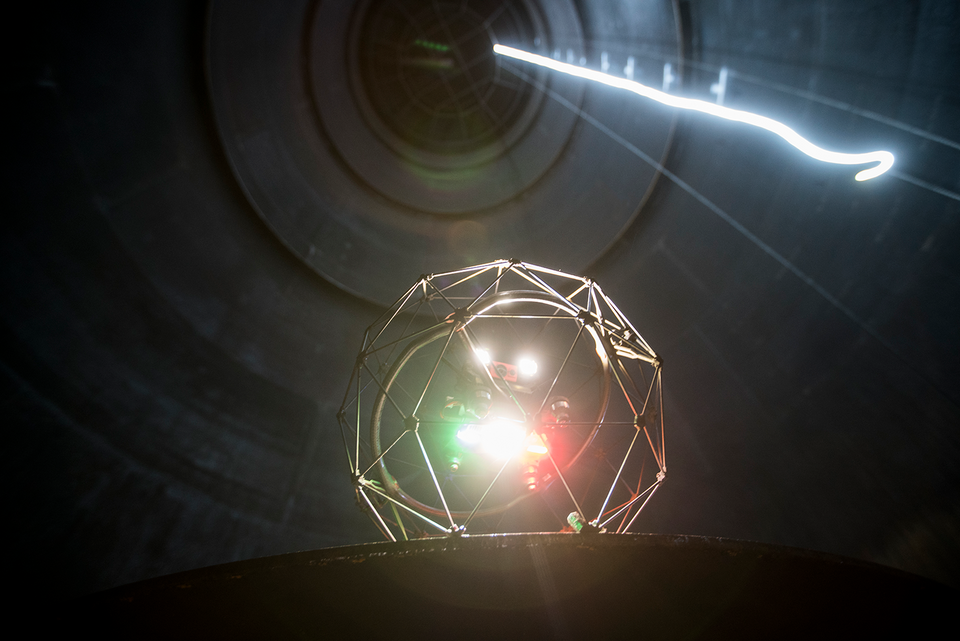 Bolldrönare med en lysande lampa inspekterar insidan av ett mörkt rör och andra trånga utrymmen i industrimiljö.