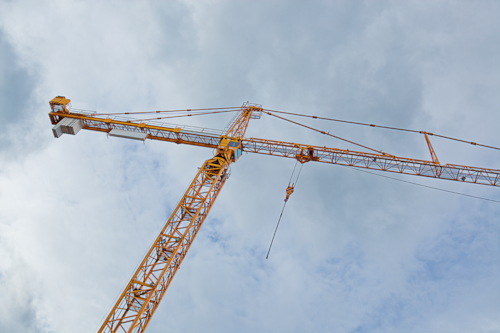Gul byggkran mot en molnig himmel.