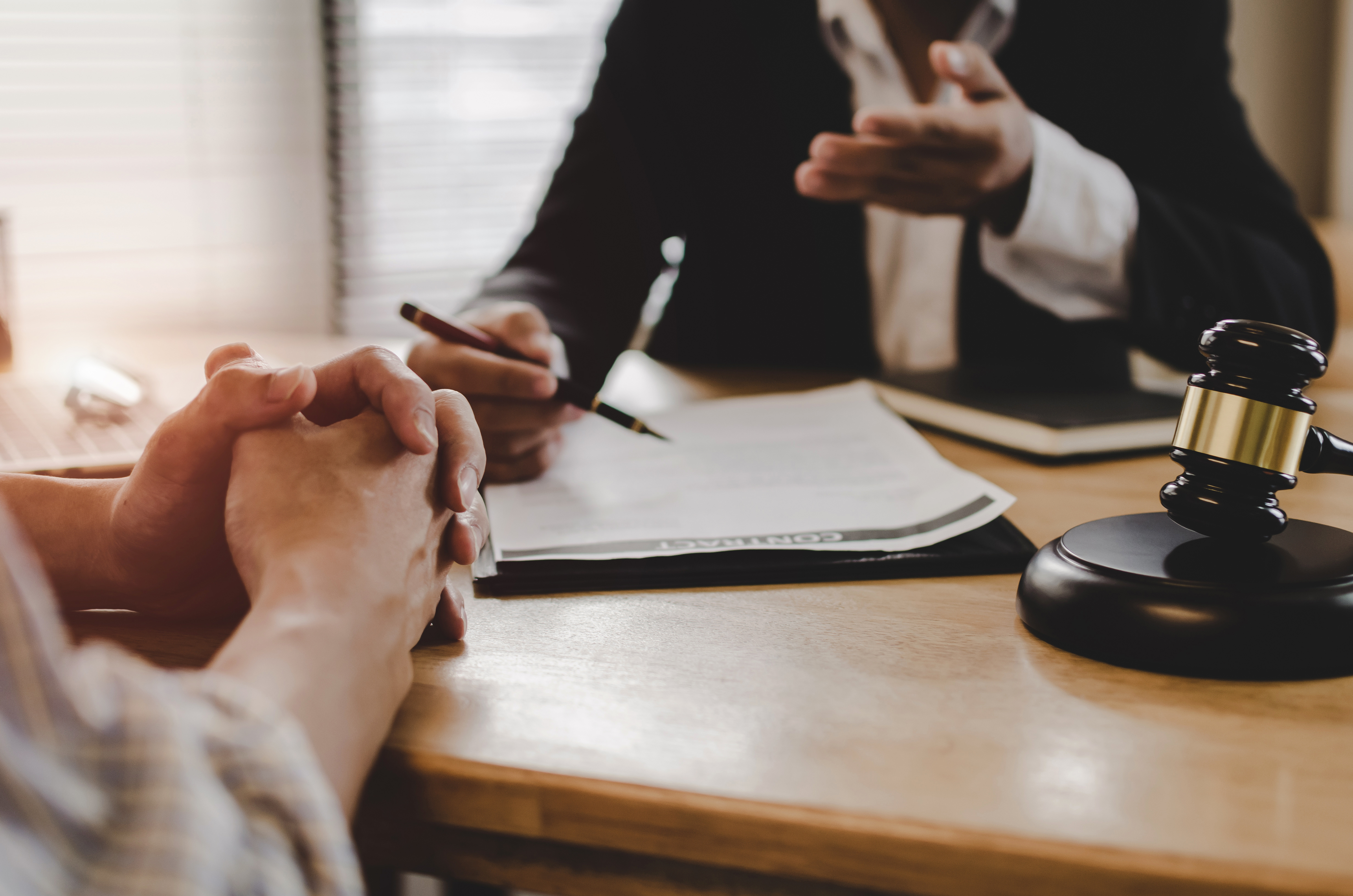 Legal consultation with client and lawyer discussing documents, with gavel on the desk