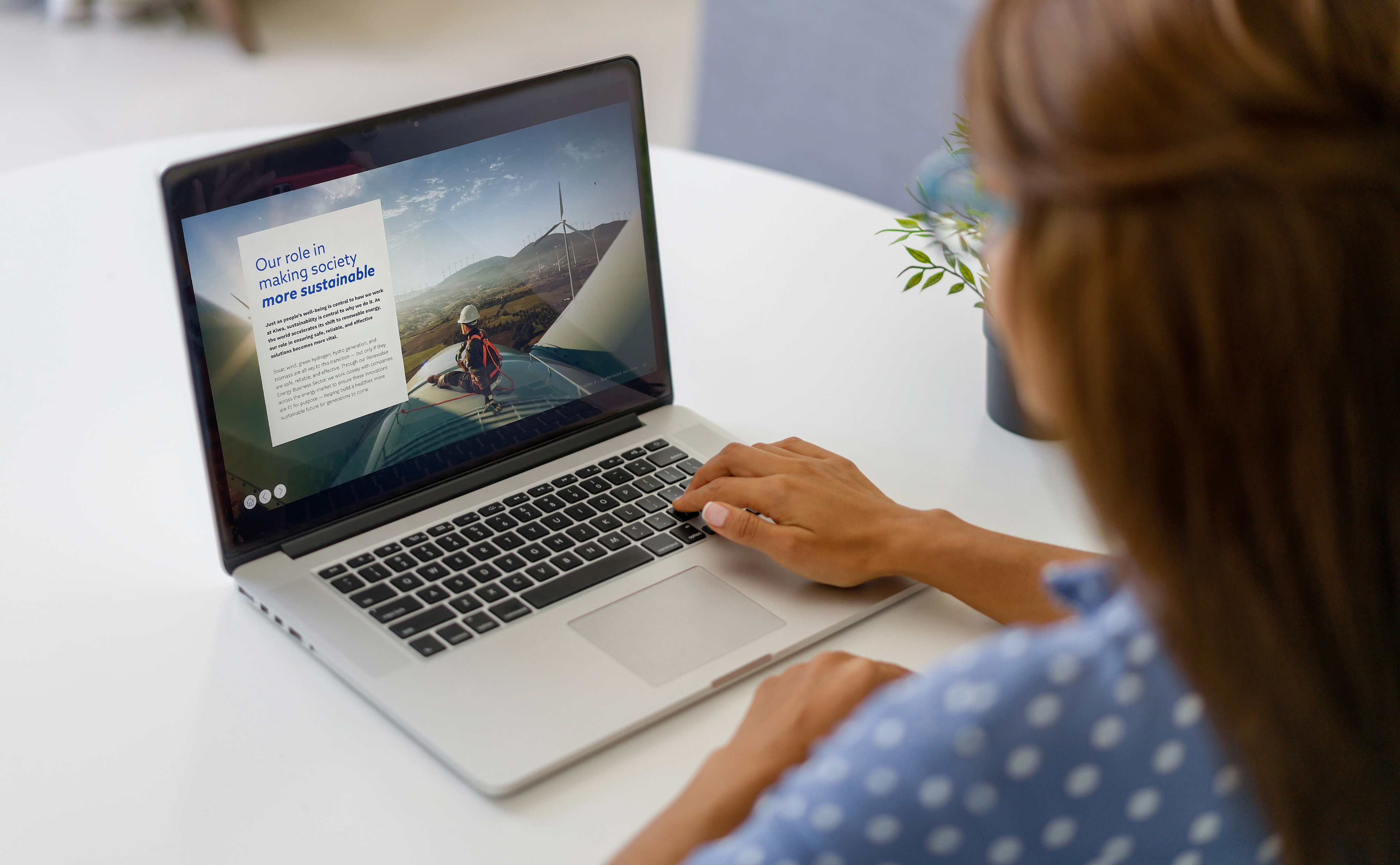 Woman in a blue polka-dot shirt using a laptop displaying Trace magazine - Kiwa’s first online ESG magazine
