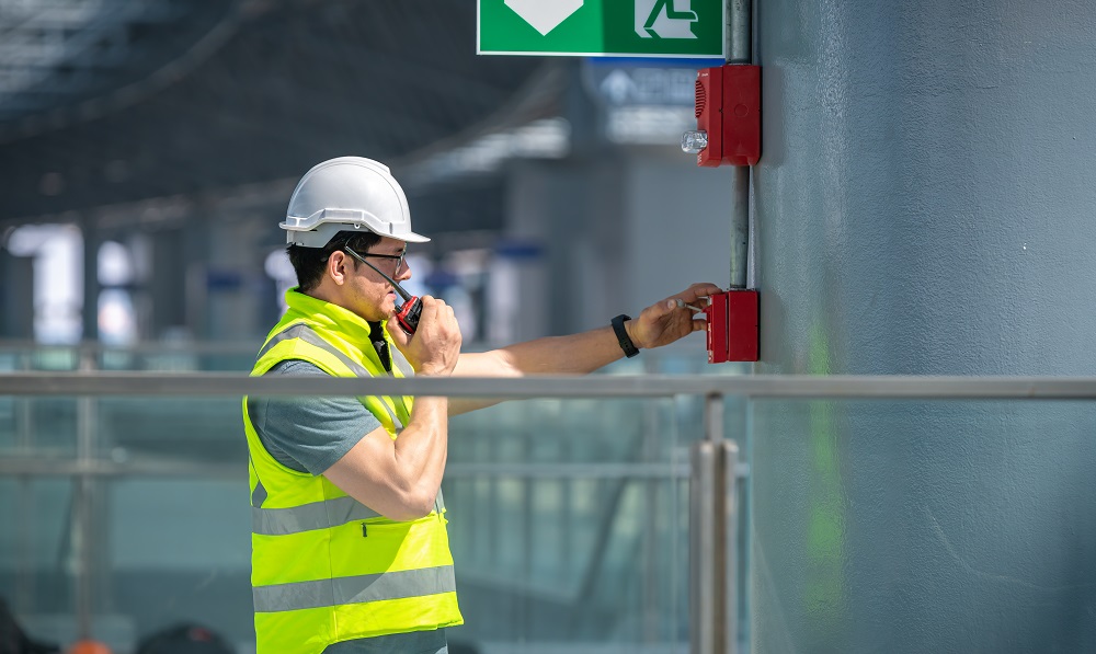 Kiwa employee in a safety vest and hard hat using a walkie-talkie.