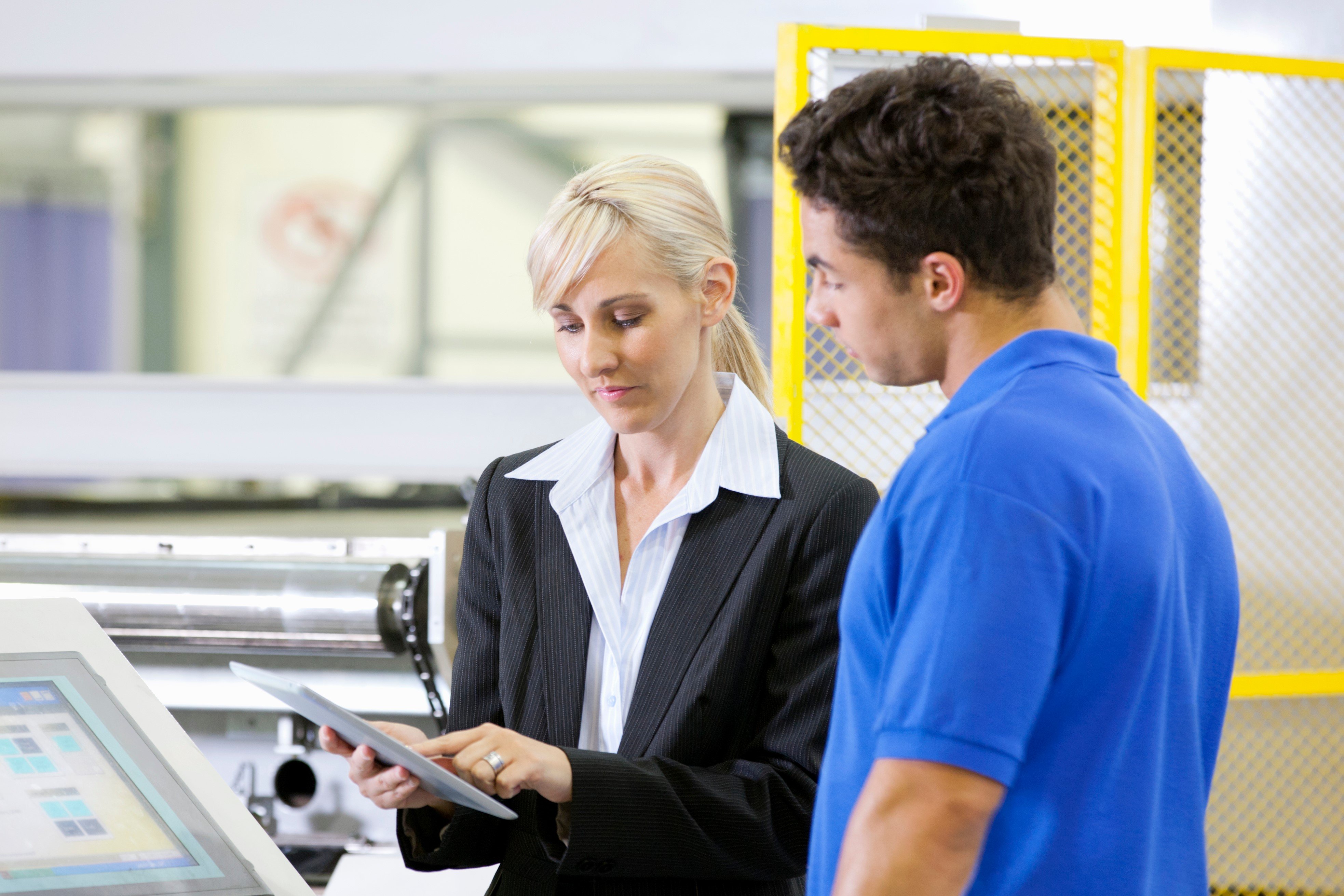 young woman assisting a male employee in a factory