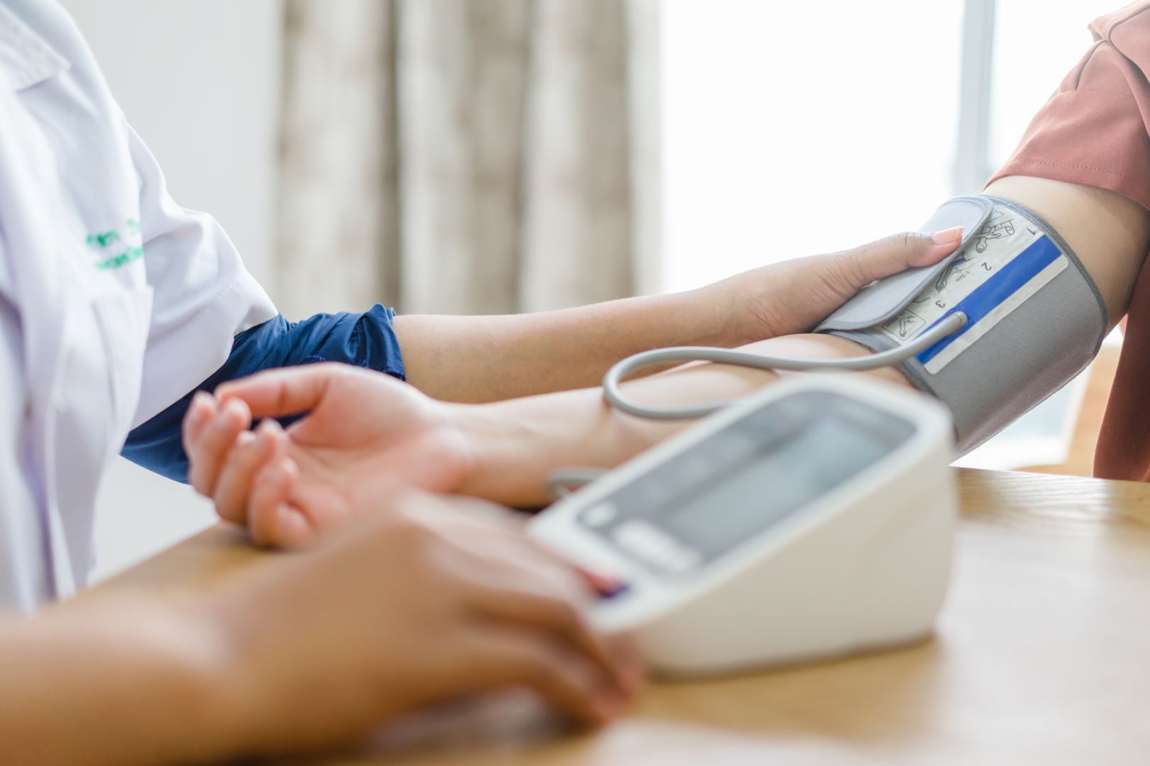Blood pressure measurement on a patient’s arm with a digital monitor in a clinic setting