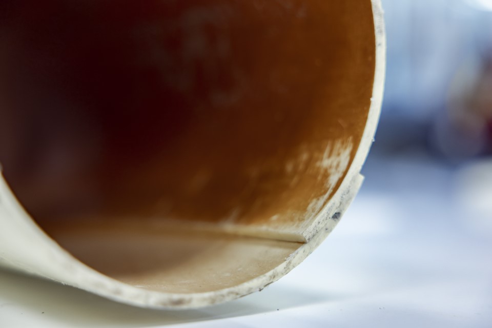 Close-up of the interior of a cylindrical object, showing a smooth, light-colored surface with some wear and a dark background.