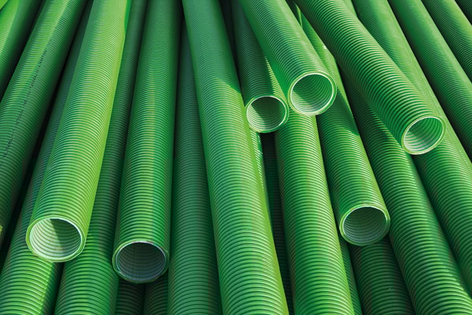Gröna korrugerade rör staplade i ett mönster.