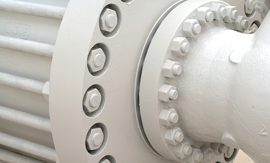 Närbild av en vit metallfläns med flera bultar och cylindriska detaljer.