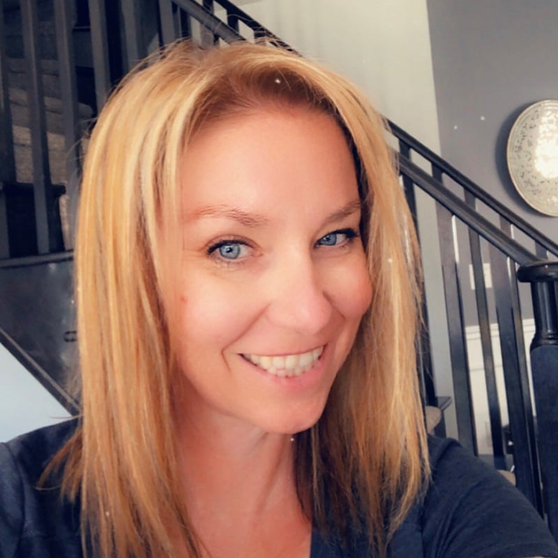 Tracy French, with blonde hair, standing indoors by a staircase